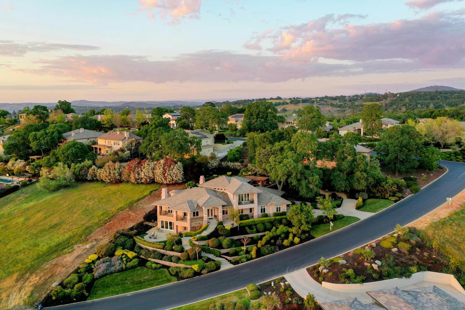 Aerial view of luxury hillside homes and landscaped streets at sunset in El Dorado Hills, CA