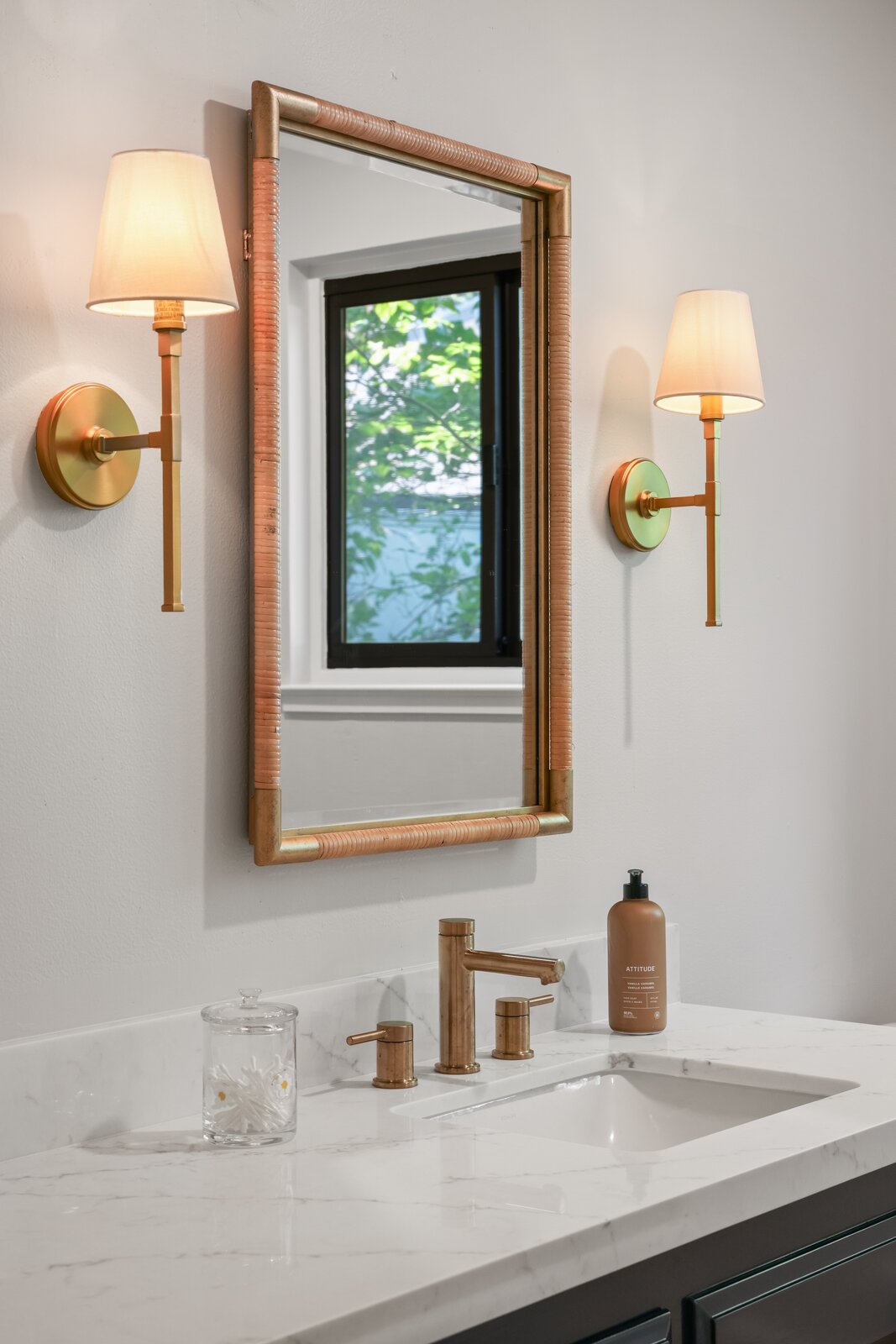 Bathroom remodel in Sacramento, CA with brass faucet, woven mirror, and brass sconces