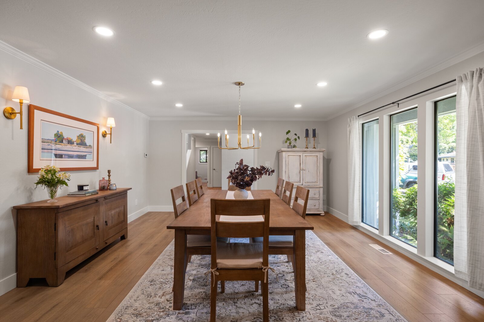 Dining room remodel in Sacramento, CA with crystal chandelier, wood armoire, and large windows