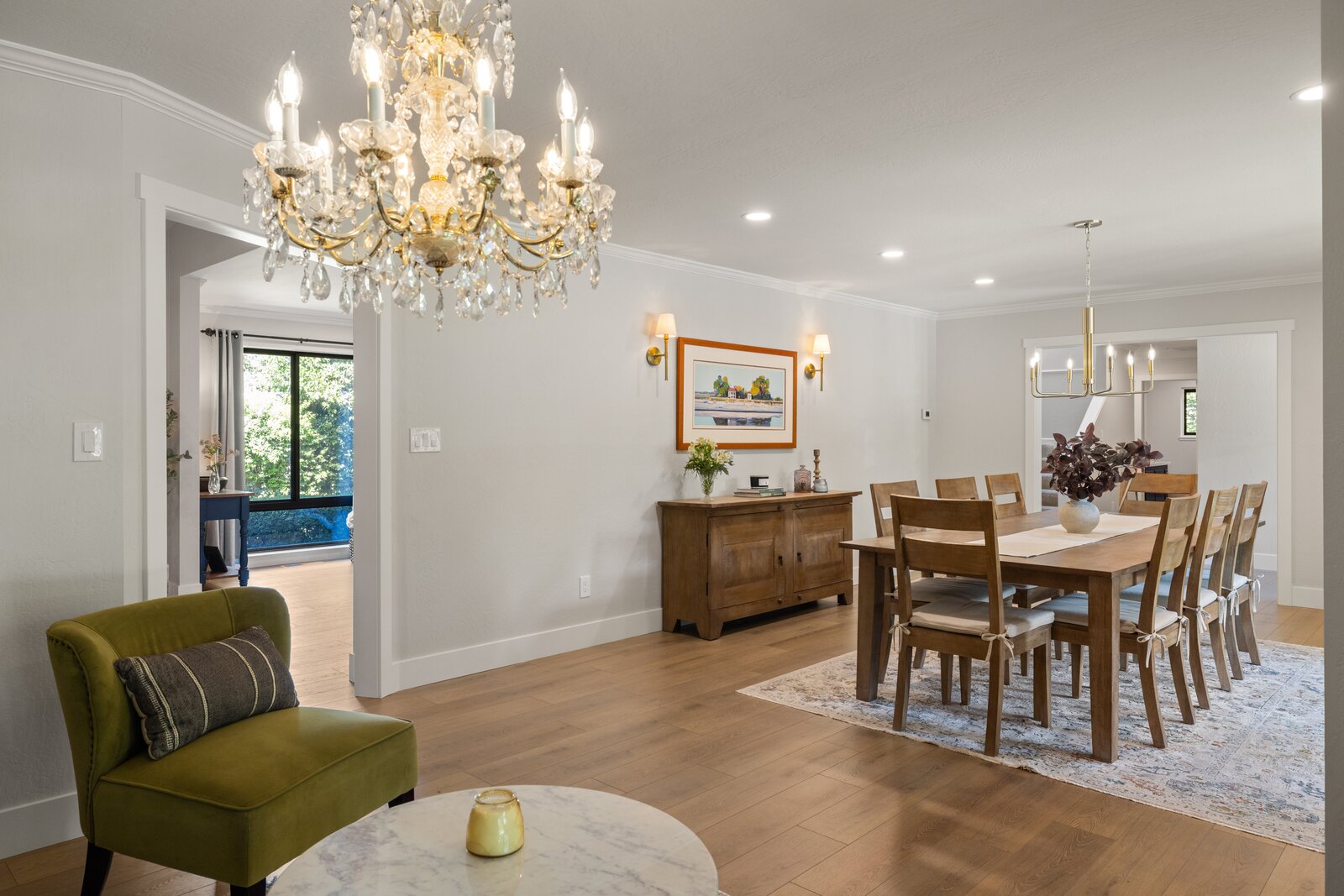Dining room remodel in Sacramento, CA with crystal chandelier, wood table, and green accent chair
