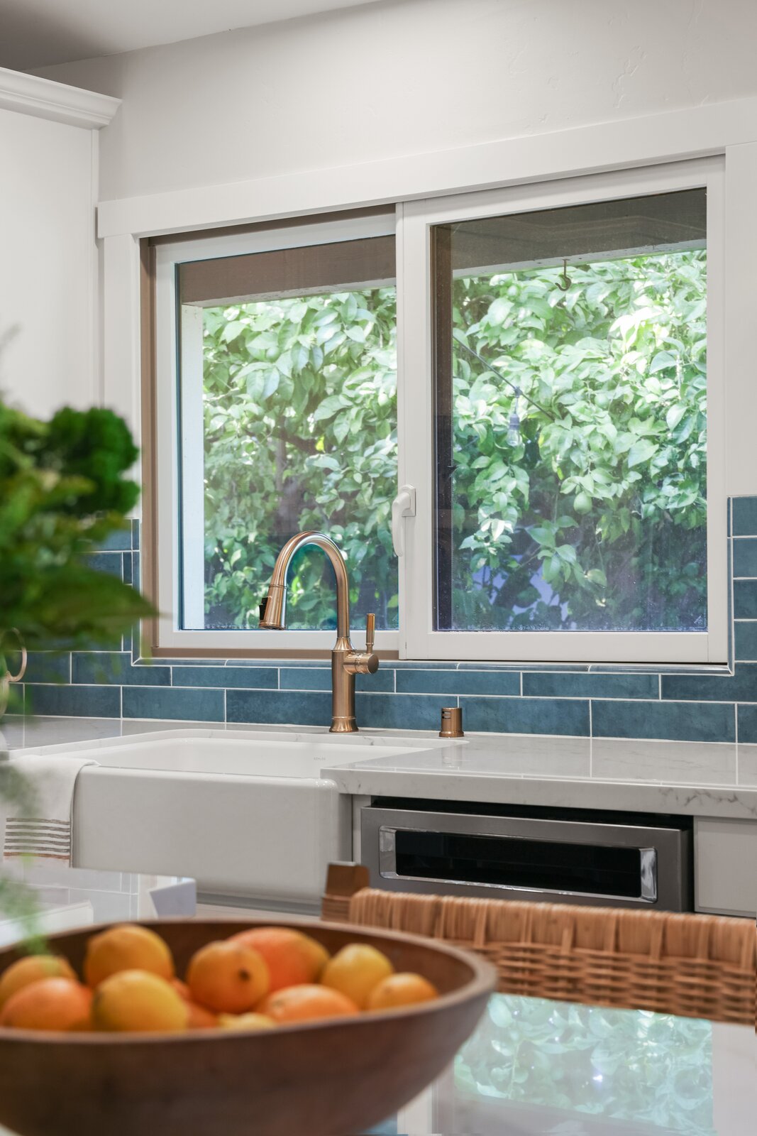 Kitchen remodel in Sacramento, CA with copper faucet, blue subway tile, and farmhouse sink view
