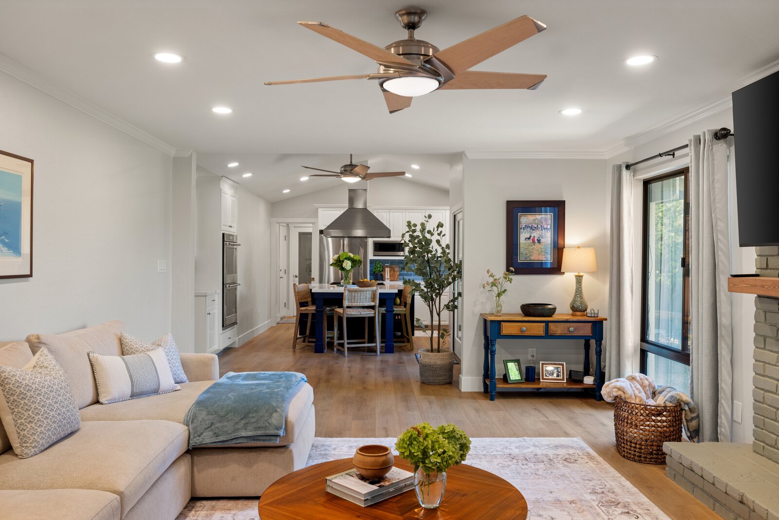 Living room remodel in Sacramento, CA with beige sectional, blue console table, and open kitchen view
