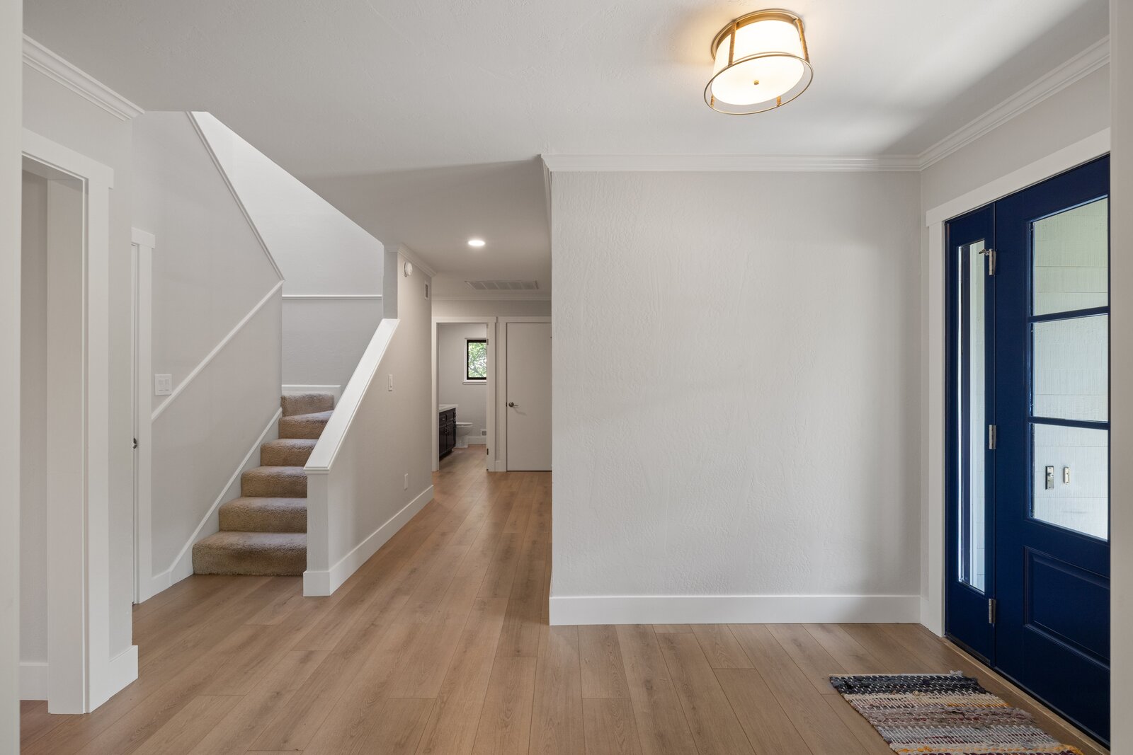 Remodeled entryway in Sacramento, CA with wood flooring, staircase, and navy front door