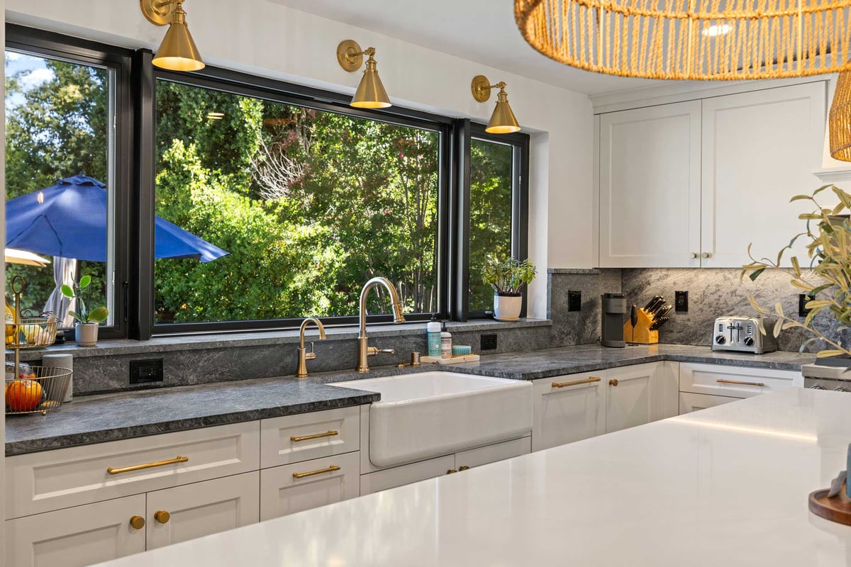 Bright Sacramento kitchen by H&H Builds with black-trim windows, gold fixtures, and stone countertops