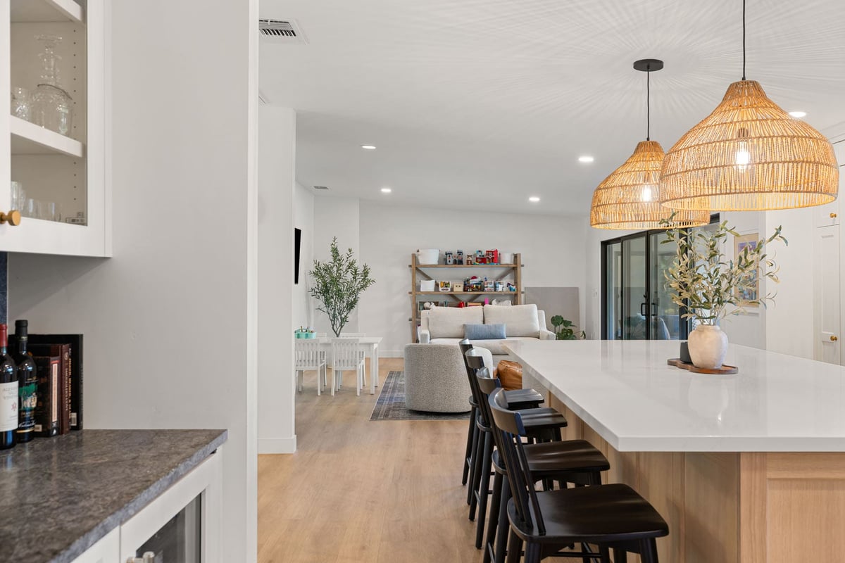 Bright open kitchen by H&H Builds in Sacramento, CA with island seating, black chairs, and view into the family room