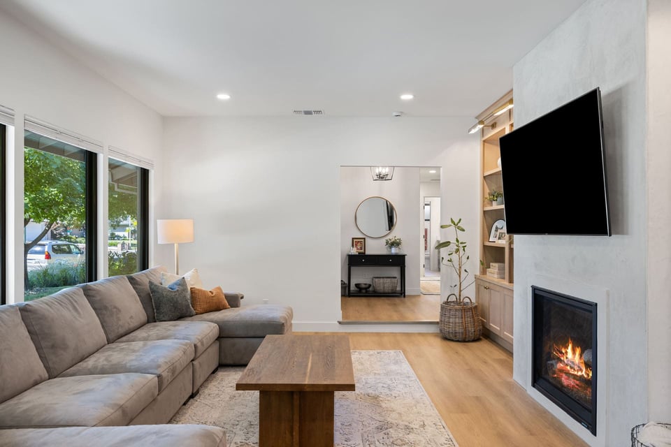 Elegant living in Sacramento with large windows, neutral sectional, fireplace, and wood built-ins