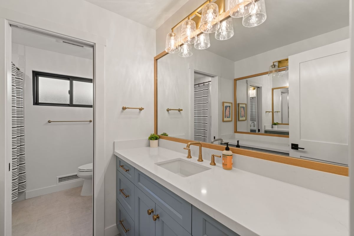Modern bath by H&H Builds in Sacramento with gold lighting, and soft white finishes