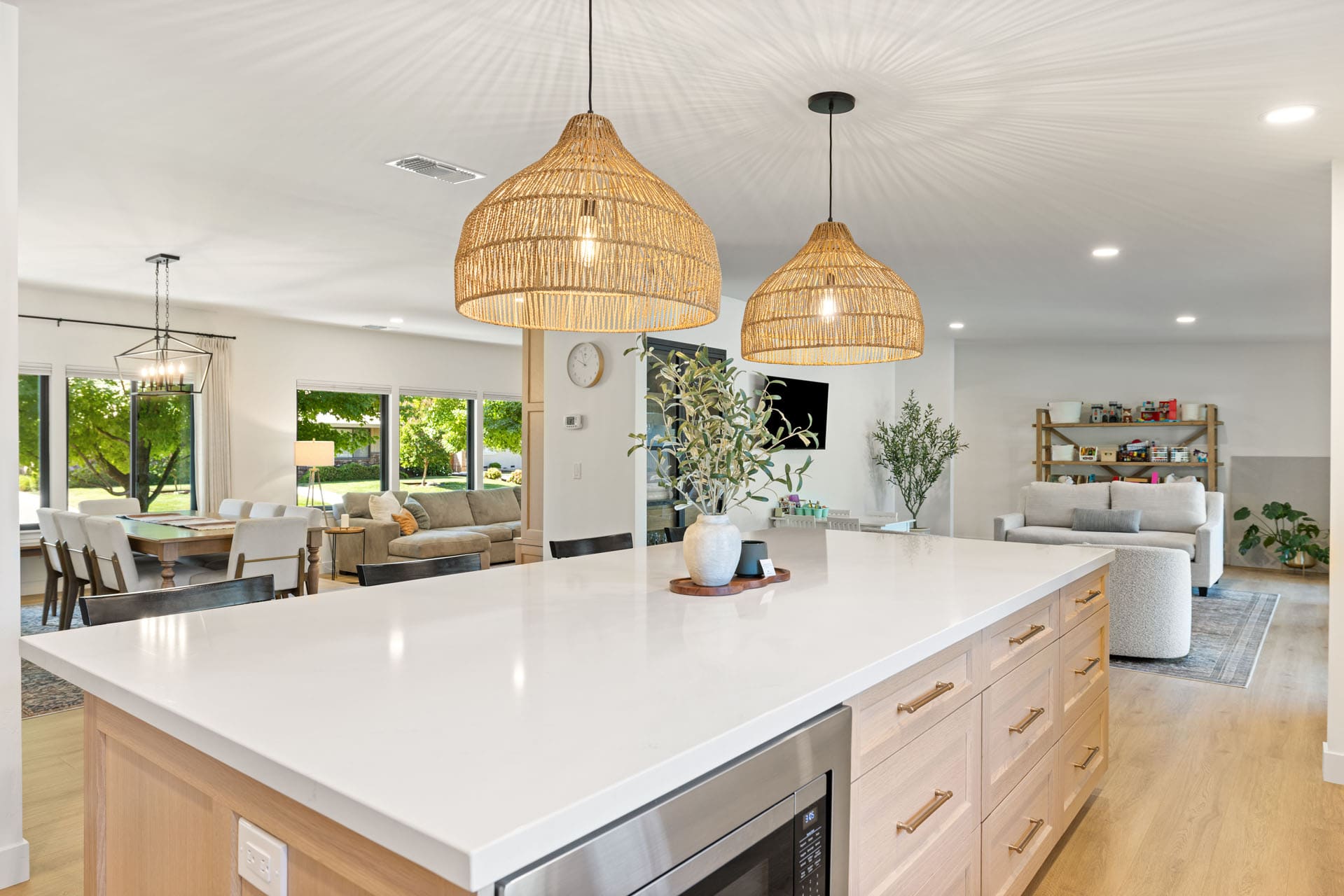 Open-concept kitchen and living space in Sacramento by H&H Builds with woven pendant lights and white island