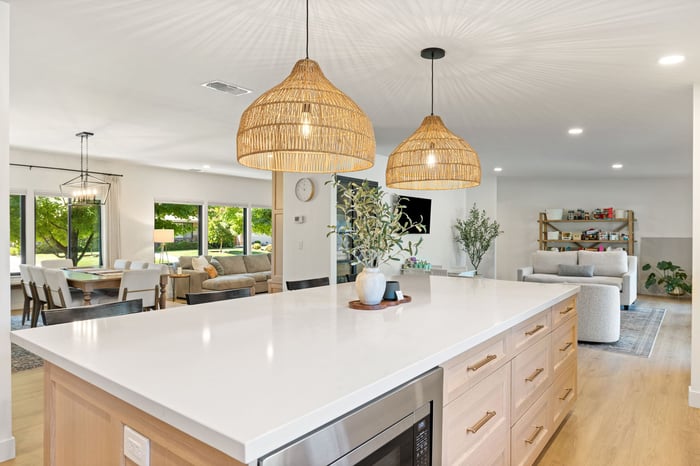 Open-concept kitchen and living space in Sacramento by H&H Builds with woven pendant lights and white island