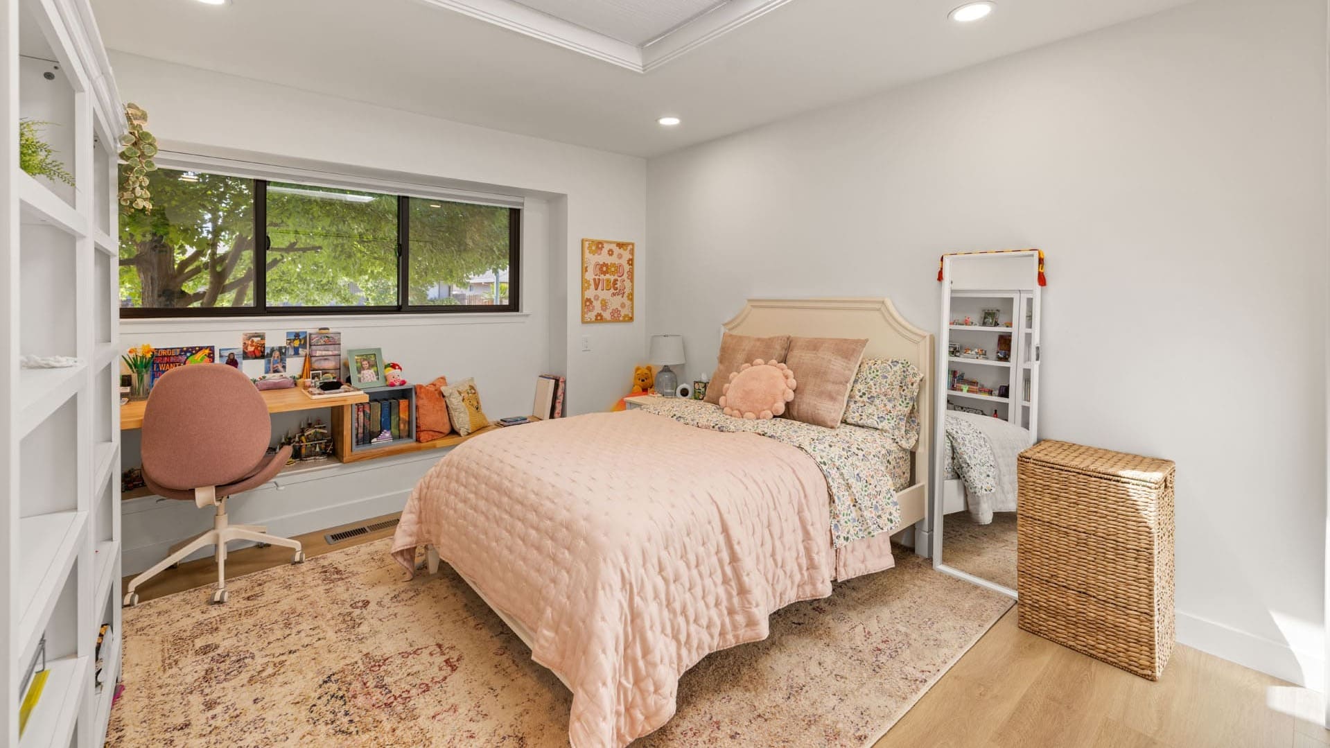 Remodeled bedroom by H&H Builds in Sacramento with skylight, pink bedding, and long desk with books and art