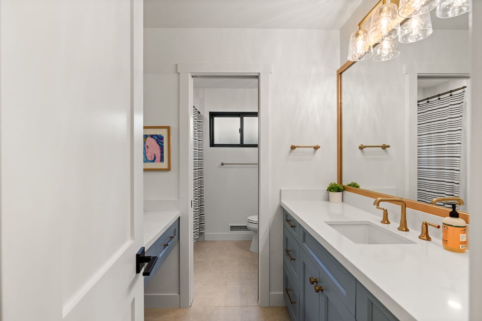 Sacramento bathroom with blue vanity, white countertop, brass fixtures, and shower beyond