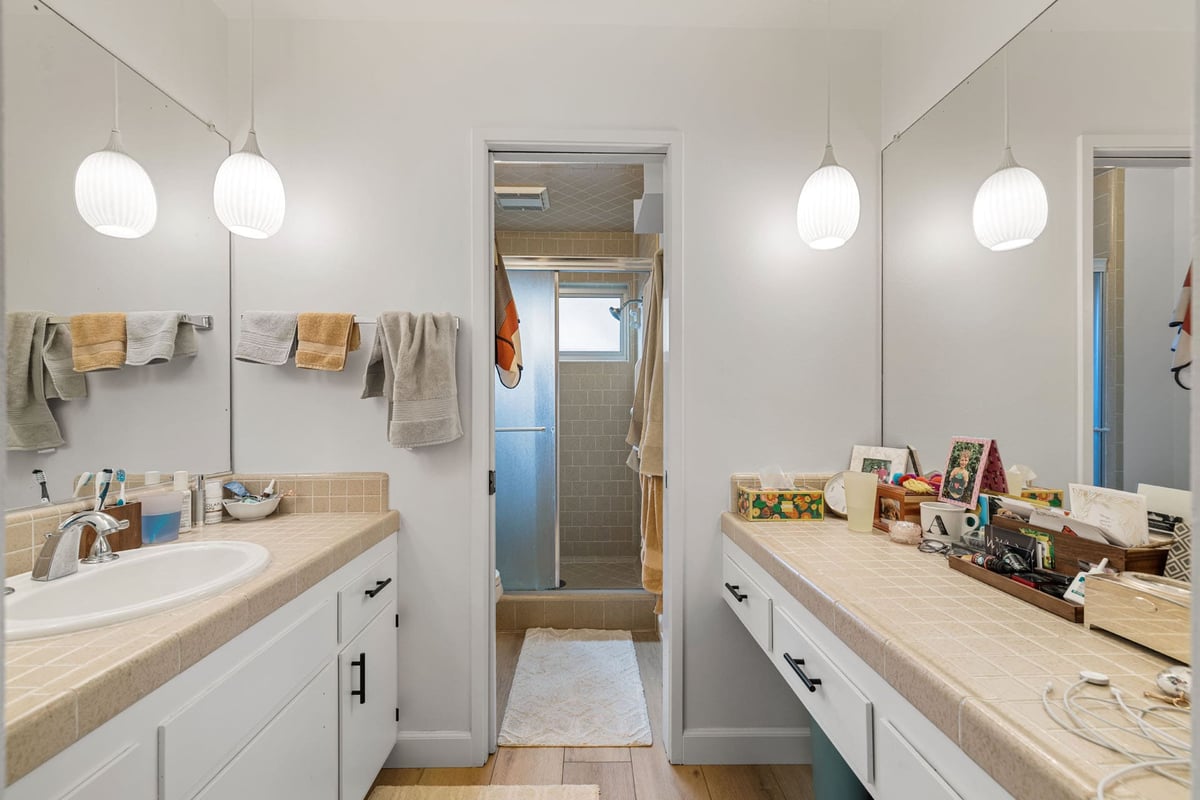 BEFORE primary bathroom in Sacramento with tile counters, pendant lights, and dual vanity layout