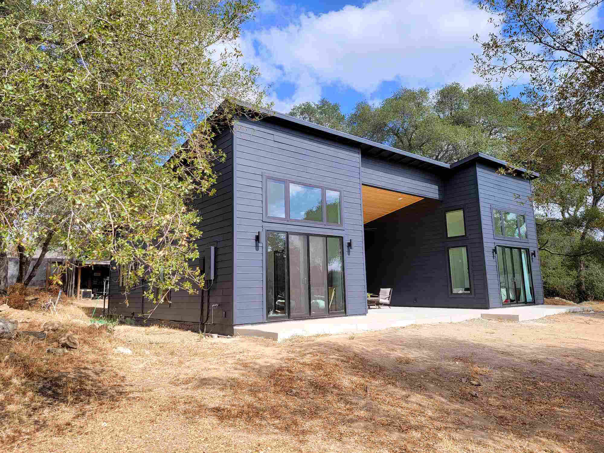 Modern black exterior custom home with large windows surrounded by trees in Sacramento, CA by H&H Builds-1