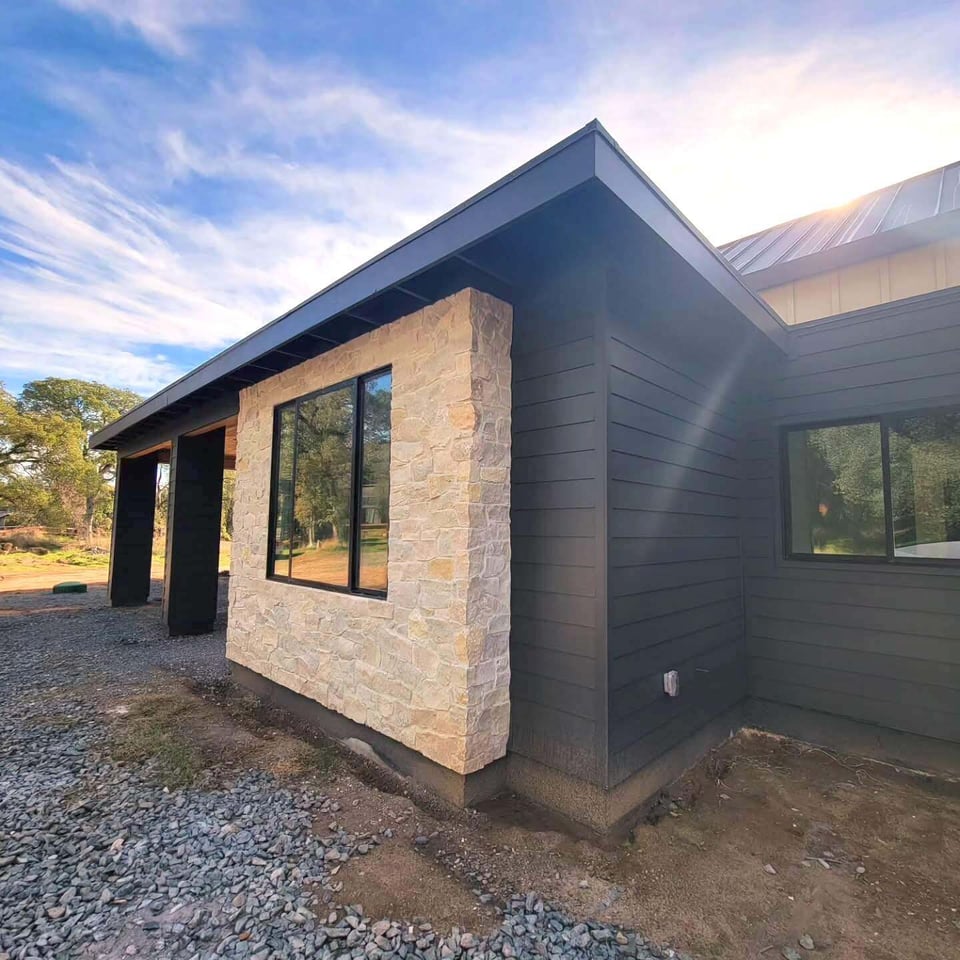 Exterior corner view of a custom-built modern home with black siding and stonework, Sacramento, CA by H&H Builds