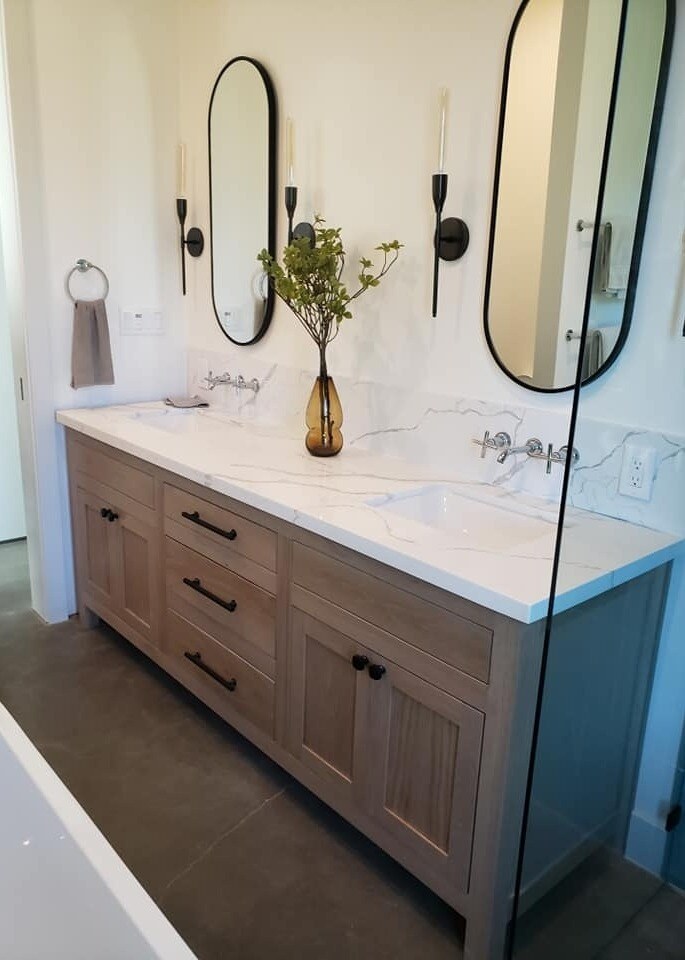 Remodeled bathroom with dual sinks, wooden cabinetry, and modern oval mirrors by H&H Builds in Sacramento, CA