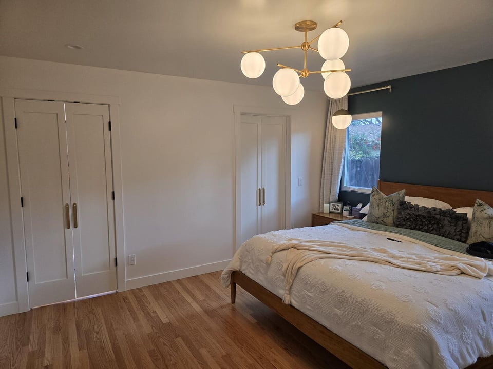 Stylish bedroom remodel with custom closet doors, modern chandelier, and a green accent wall by H&H Builds, Sacramento, CA