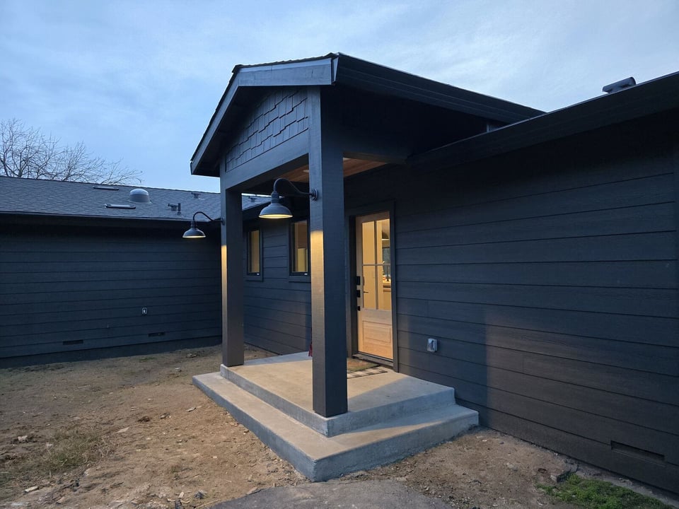 Modern black home remodel entrance with a covered porch and sleek lighting in Sacramento, CA, by H&H Builds