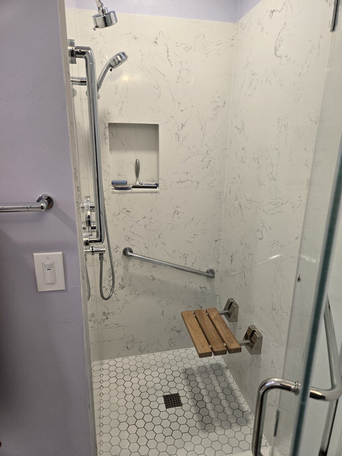 Modern walk-in shower with wall niche, folding seat, and chrome fixtures by H&H Builds in Sacramento, CA