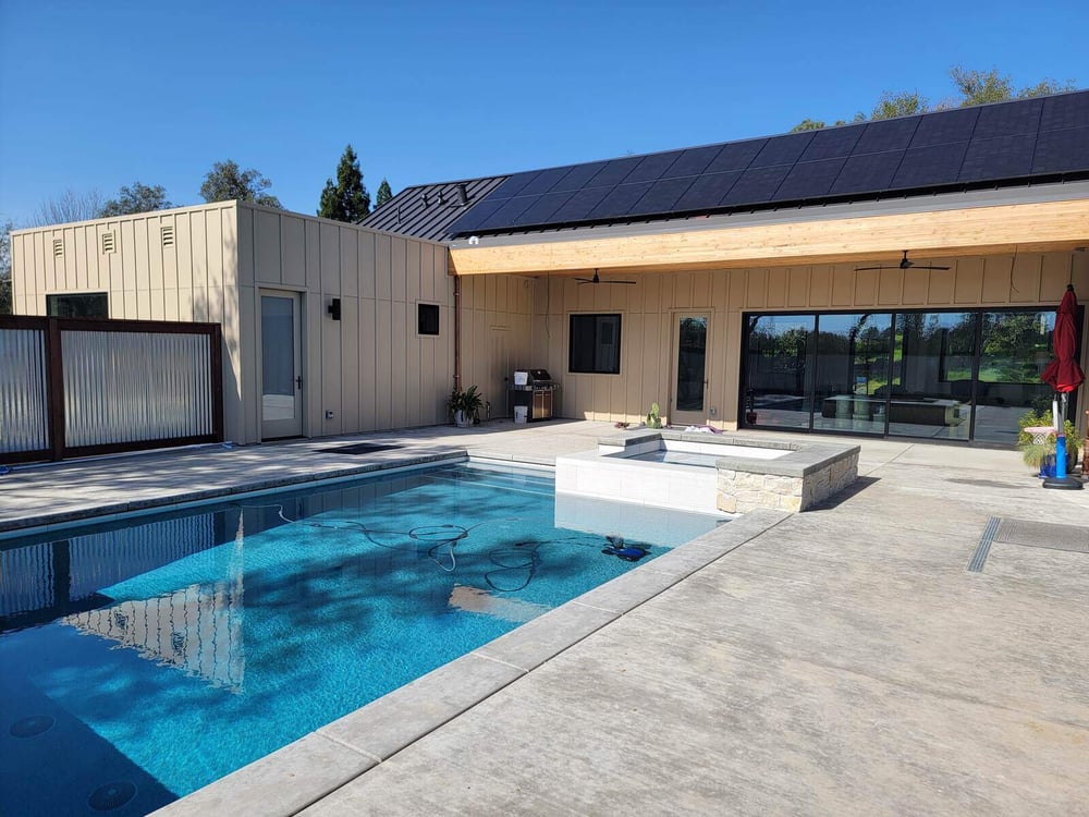 Outdoor remodel featuring a swimming pool, spa, and modern patio area with solar-paneled roofing by H&amp;H Builds in Sacramento, CA