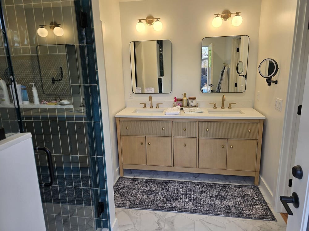 Remodeled bathroom with a wooden double vanity, gold fixtures, and glass shower enclosure by H&H Builds, Sacramento, CA