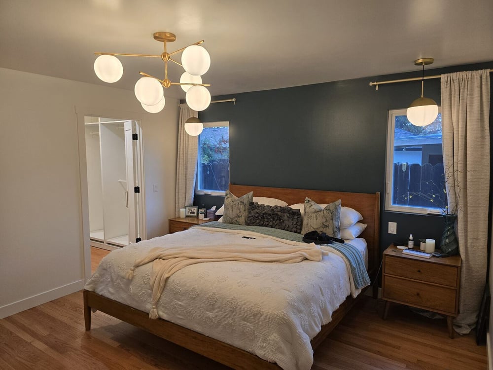 Remodeled master bedroom with wood flooring, modern chandelier, and accent wall by H&H Builds, Sacramento, CA