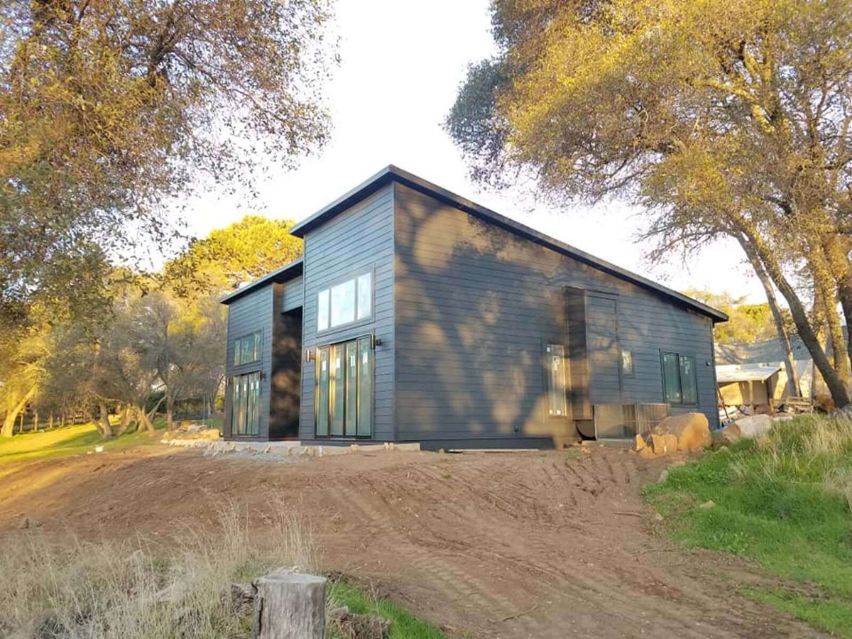 Side view of a modern black home remodel surrounded by trees in Sacramento, CA, by H&amp;H Builds