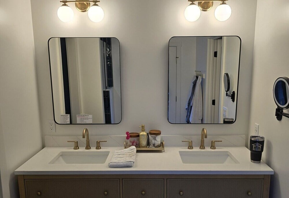 Wide view of remodeled bathroom with dual vanity, gold fixtures, and decorative mirrors by H&H Builds, Sacramento, CA