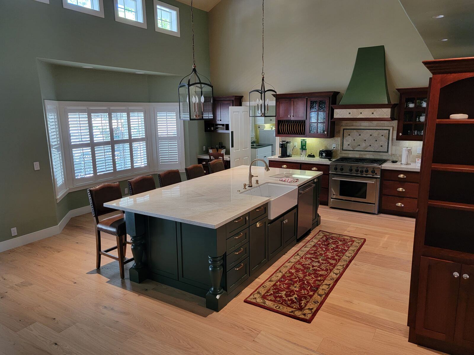 Spacious kitchen remodel with green cabinetry, large island, and wood floors by H&H Builds in Sacramento, CA