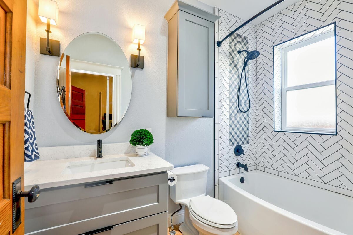 Bright and elegant bathroom remodel by H&H Builds in Sacramento, CA, showcasing a herringbone tile shower and modern vanity