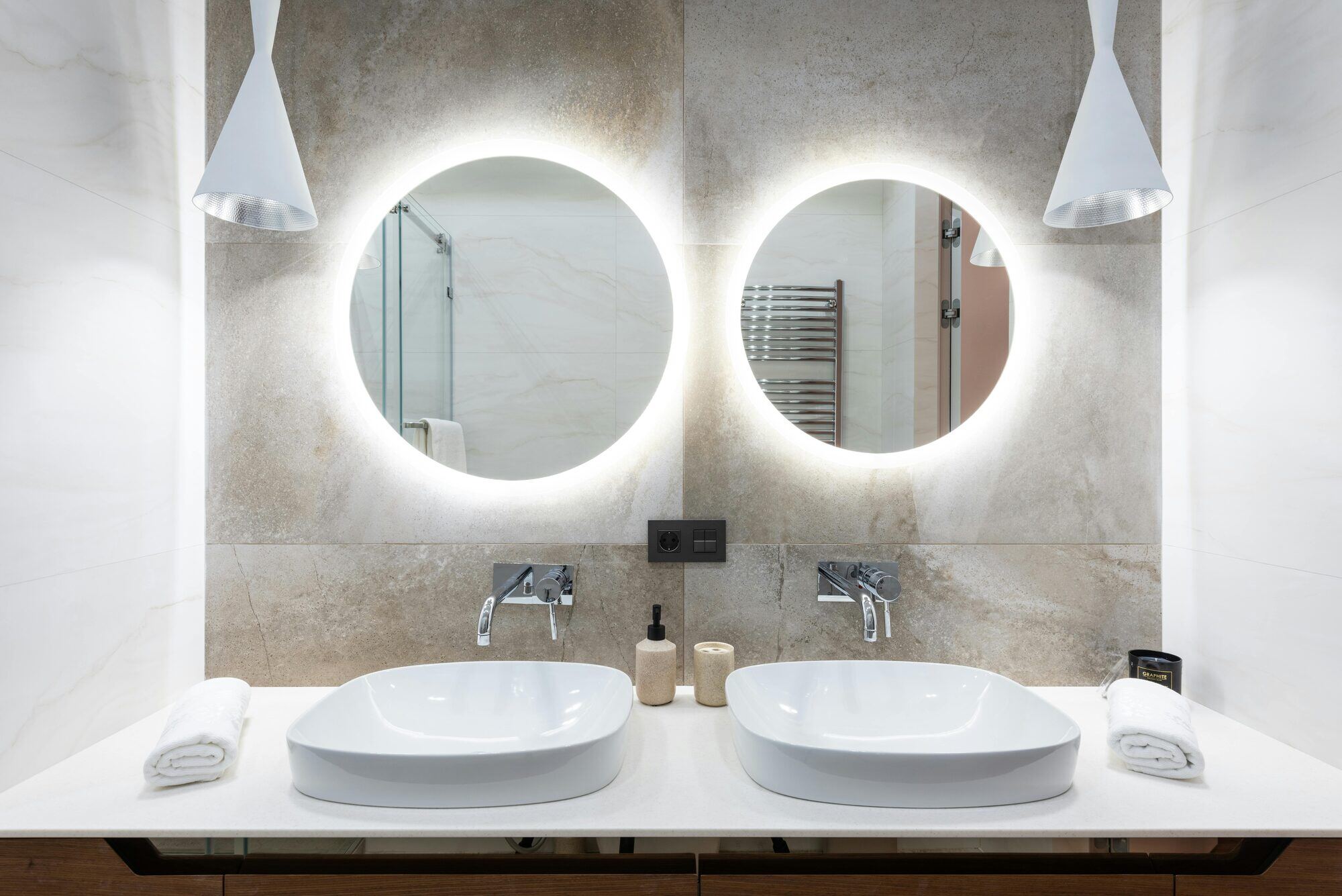 Modern bathroom remodel featuring illuminated circular mirrors and double sinks by H&H Builds in Sacramento, CA