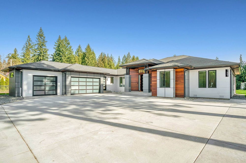 Spacious modern custom home with large garage doors, wood accents, and a wide driveway by H&H Builds in Sacramento, CA