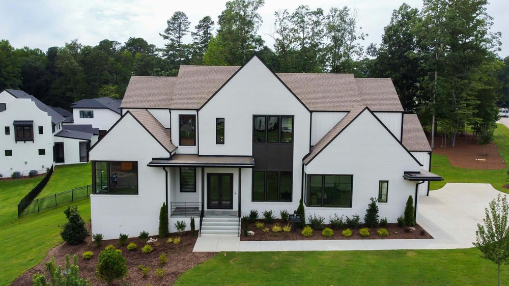 Stunning white modern farmhouse-style custom home with large windows and manicured landscaping by H&amp;H Builds in Sacramento, CA