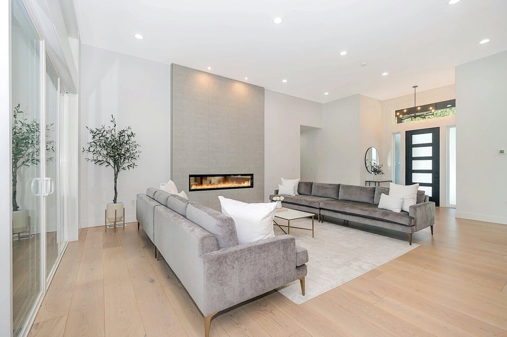 Modern living room with sleek gray sofas, a minimalist fireplace, and light wood flooring by H&H Builds in Sacramento, CA