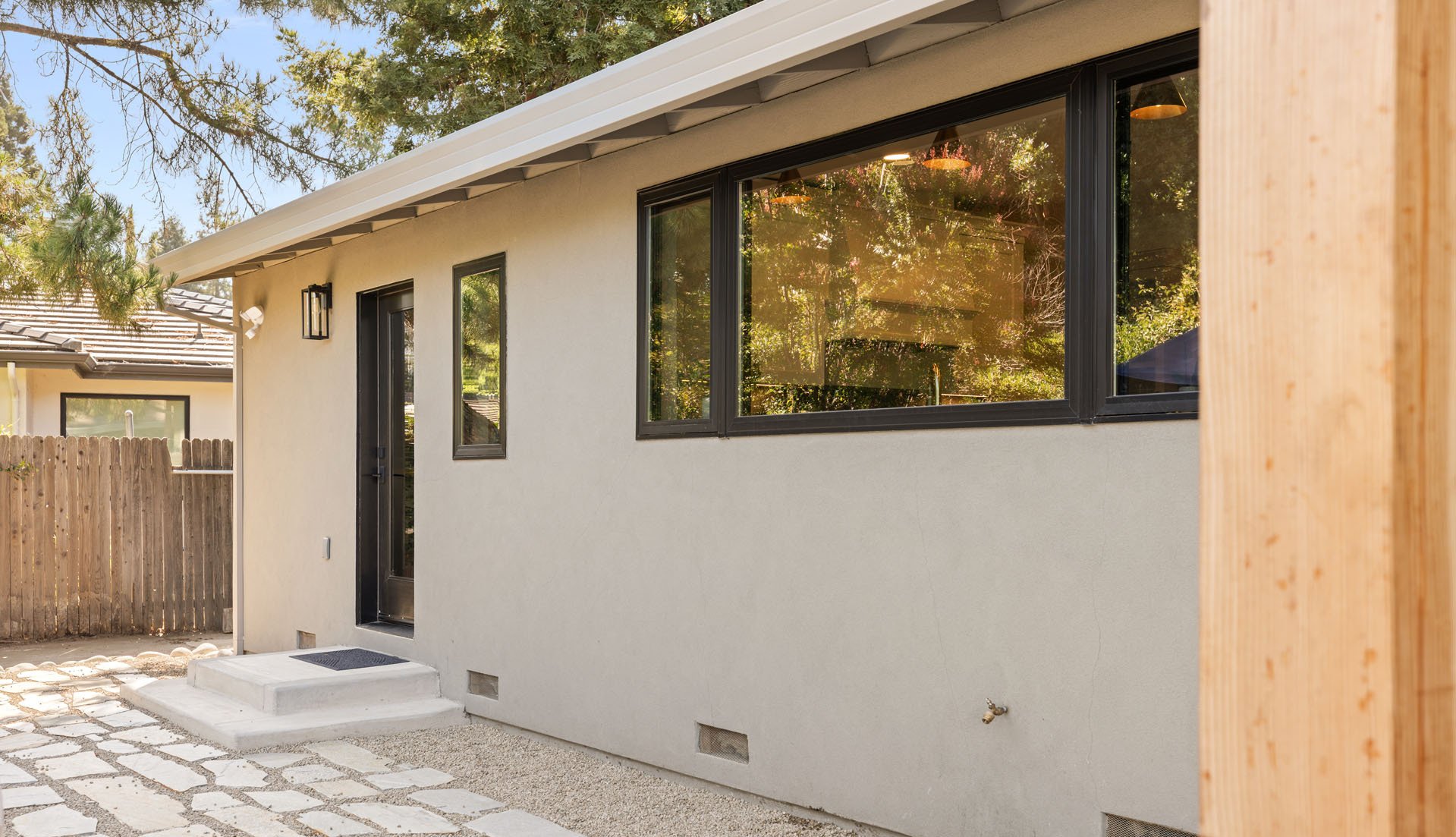 Modern Sacramento exterior by H&H Builds with smooth stucco, black trim windows, and stone walkway.