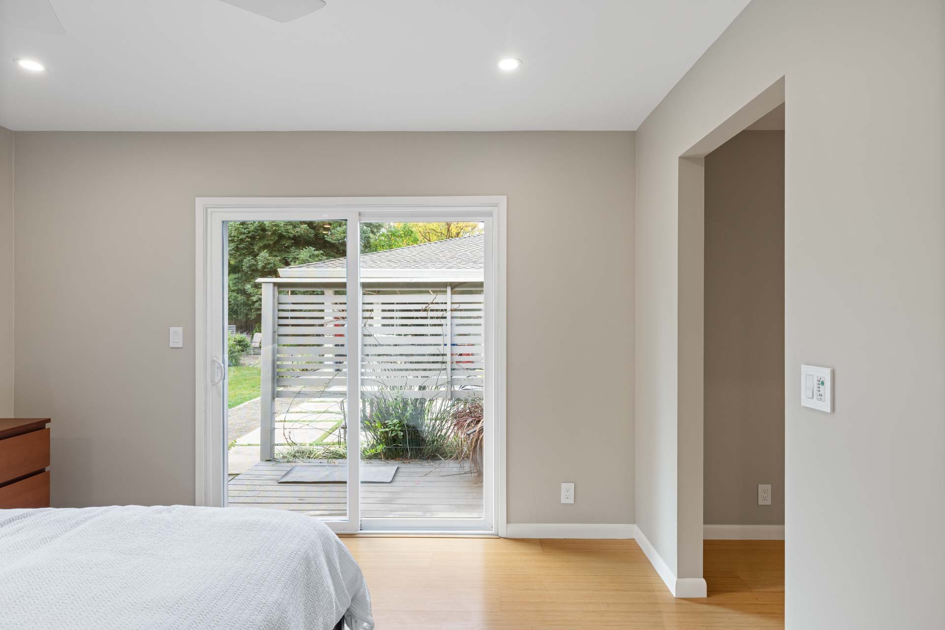 Bright Sacramento bedroom with sliding glass door to a landscaped backyard and privacy screen
