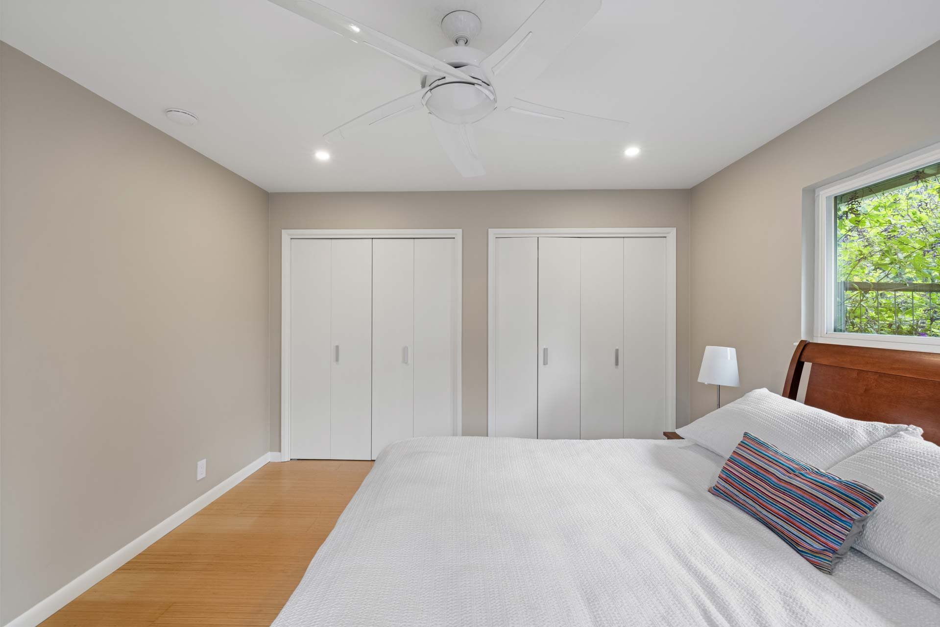 Modern Sacramento bedroom with double closets, wood floors, and a white ceiling fan above a neatly made bed