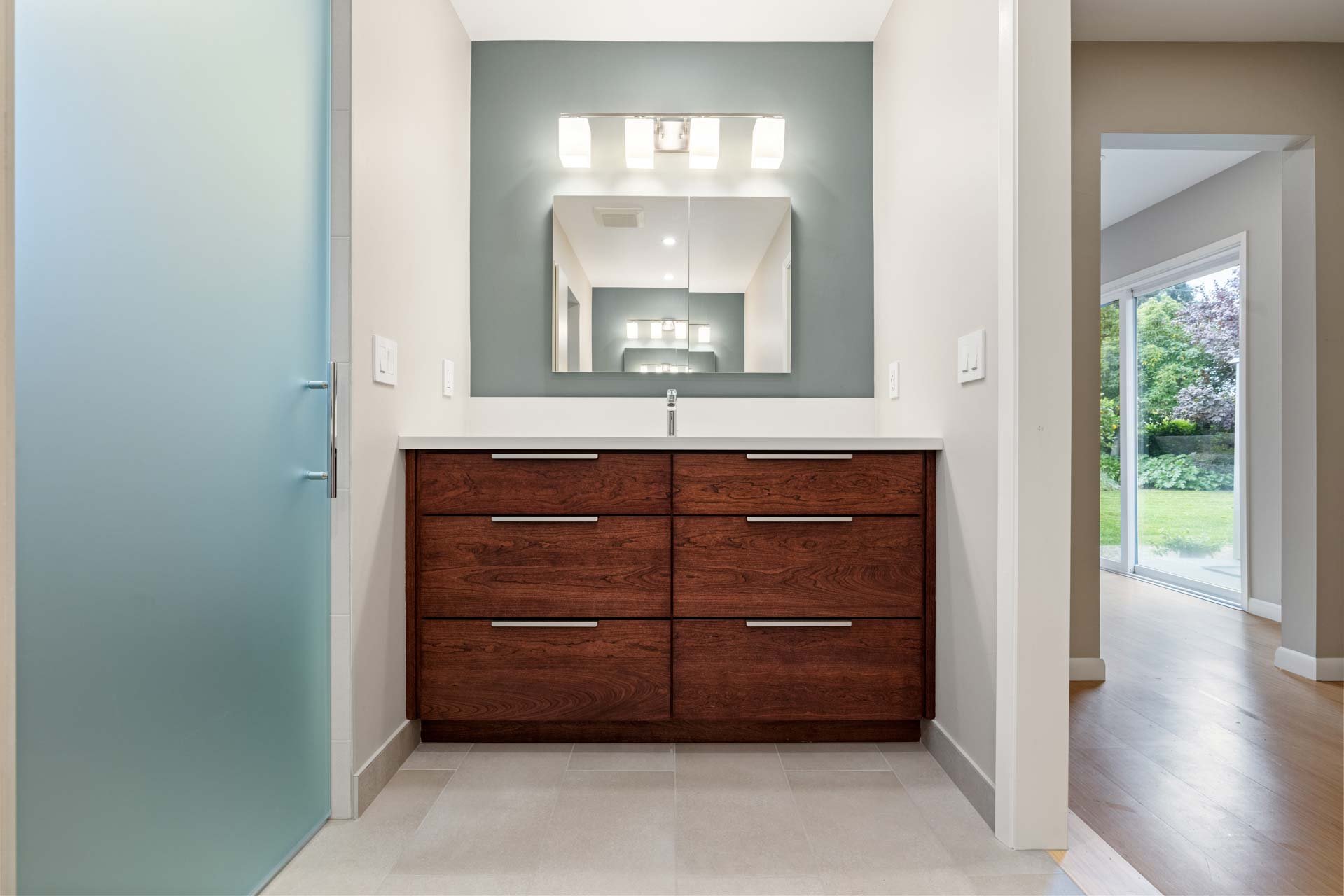 Modern bathroom vanity in Sacramento with wood drawers, white countertop, and large mirror