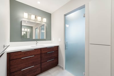 Remodeled Sacramento bathroom vanity with green accent wall, mirror, and frosted glass door