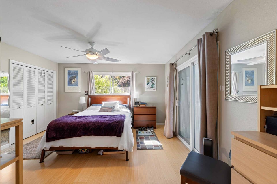 Cozy Sacramento bedroom with sliding glass door, white closet doors, and personal decor above the bed