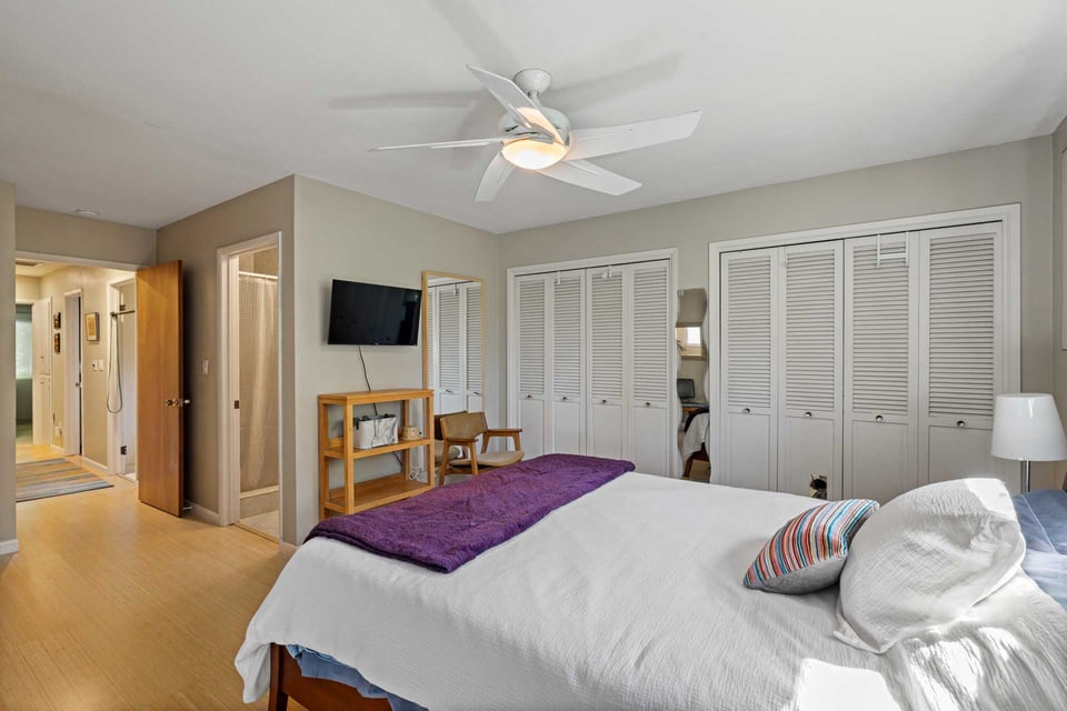 Sacramento bedroom with louvered closet doors, ceiling fan, and view into hallway and bathroom areas