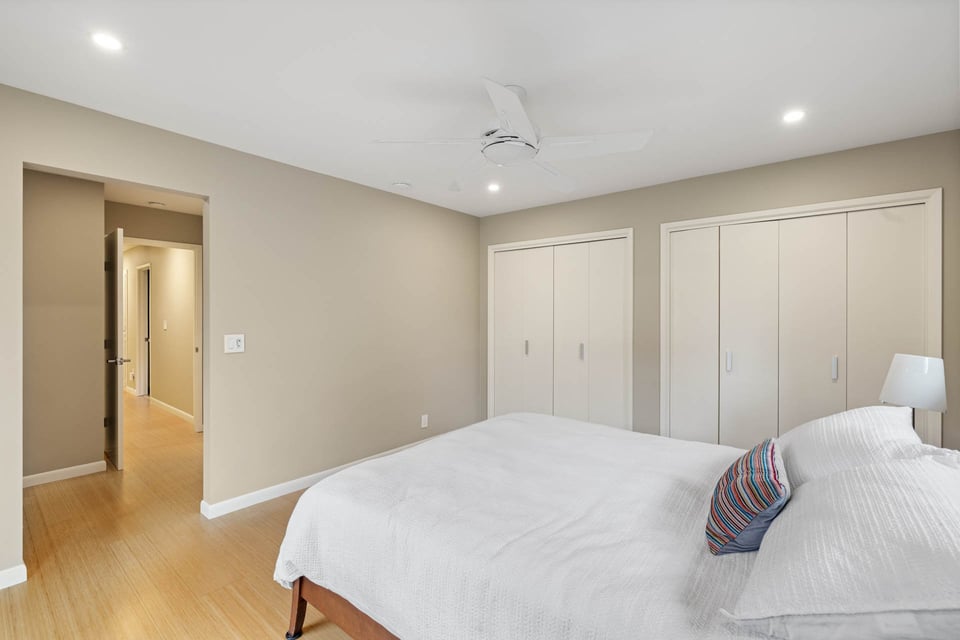 Sacramento bedroom with neutral walls, bamboo floors, dual closets, and a ceiling fan above a neatly made bed
