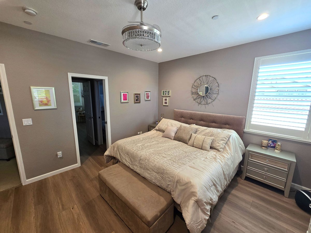 Neutral bedroom with upholstered bed, modern ceiling fan, and hardwood floors in Sacramento