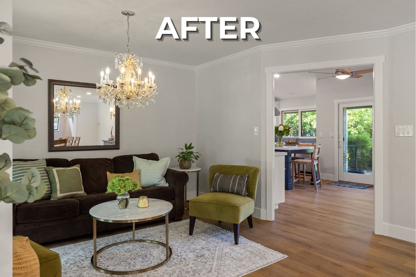 After - Refreshed sitting room with neutral walls, warm wood floors, crystal chandelier, green accents, and open kitchen access. After - Refreshed sitting room with neutral walls, warm wood floors, crystal chandelier, green accents, and open kitchen access.