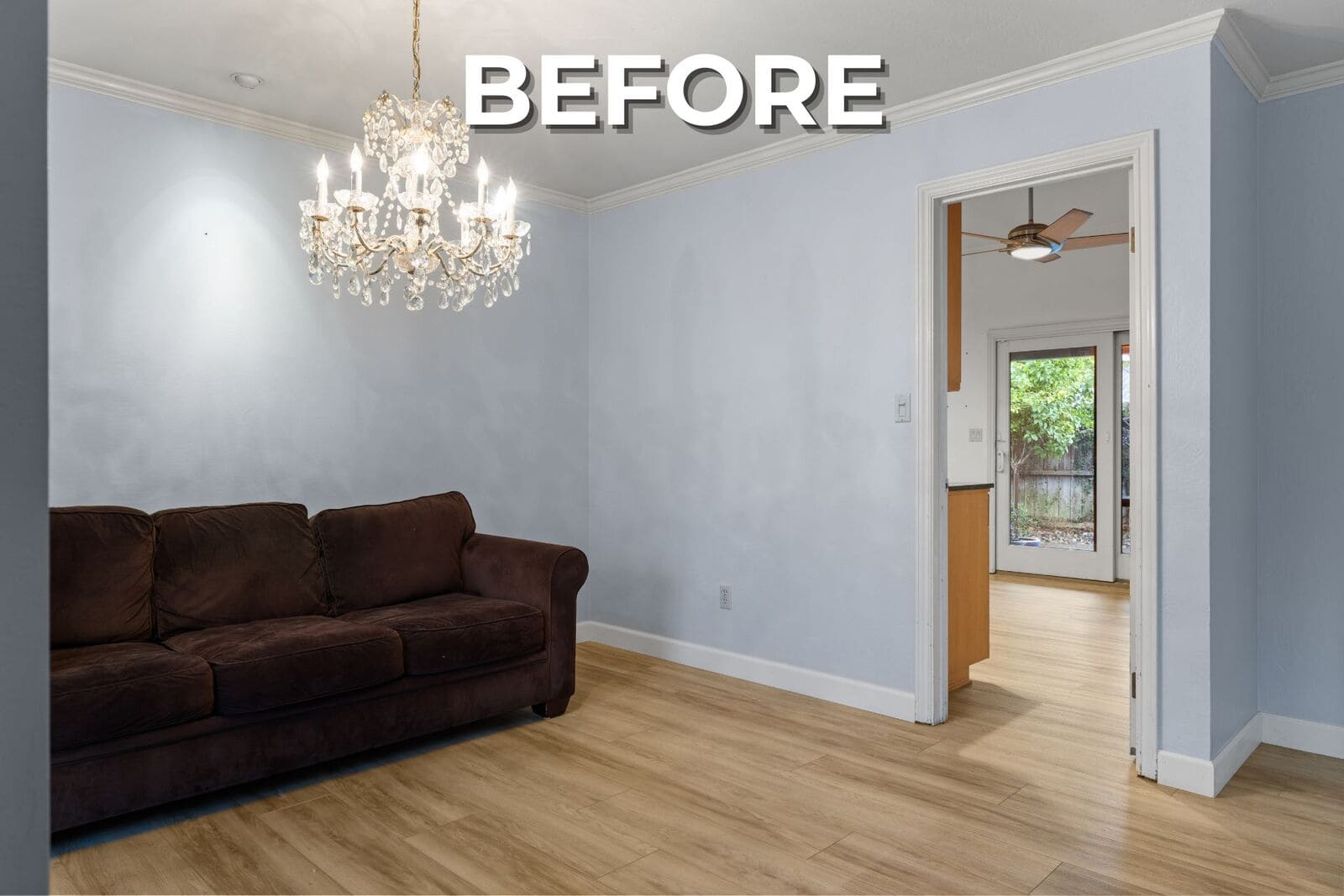Before - Light blue sitting room with wood floors, crystal chandelier, dark sofa, and a doorway leading toward the kitchen. Before - Light blue sitting room with wood floors, crystal chandelier, dark sofa, and a doorway leading toward the kitchen.