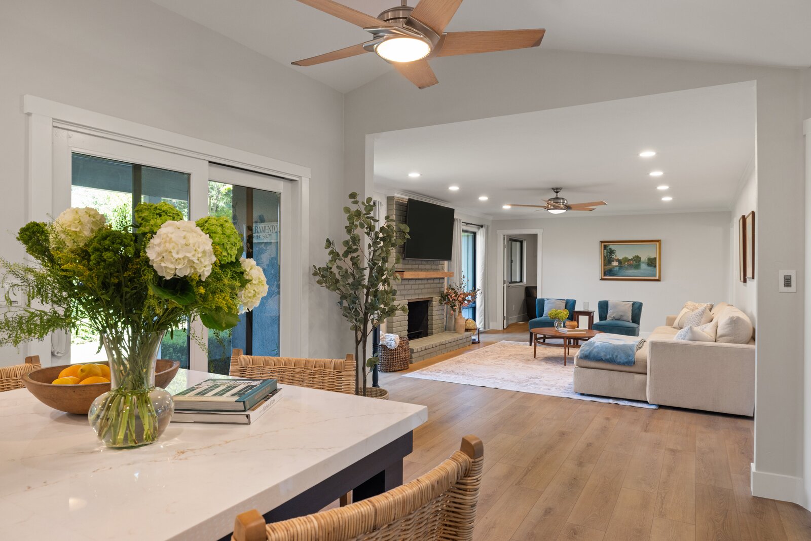 Open concept living room remodel in Sacramento, CA with brick fireplace and blue accent chairs