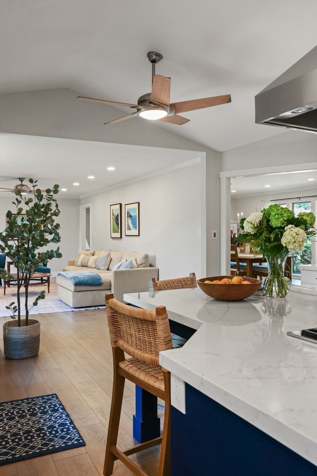 Sacramento area kitchen with navy island, woven counter stools, and open living room view