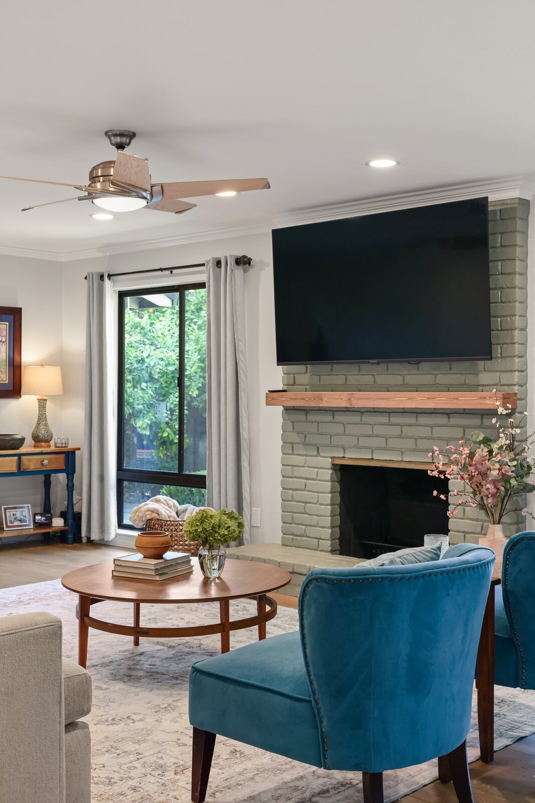 Sacramento area living room with painted brick fireplace, mounted TV, and blue accent chairs