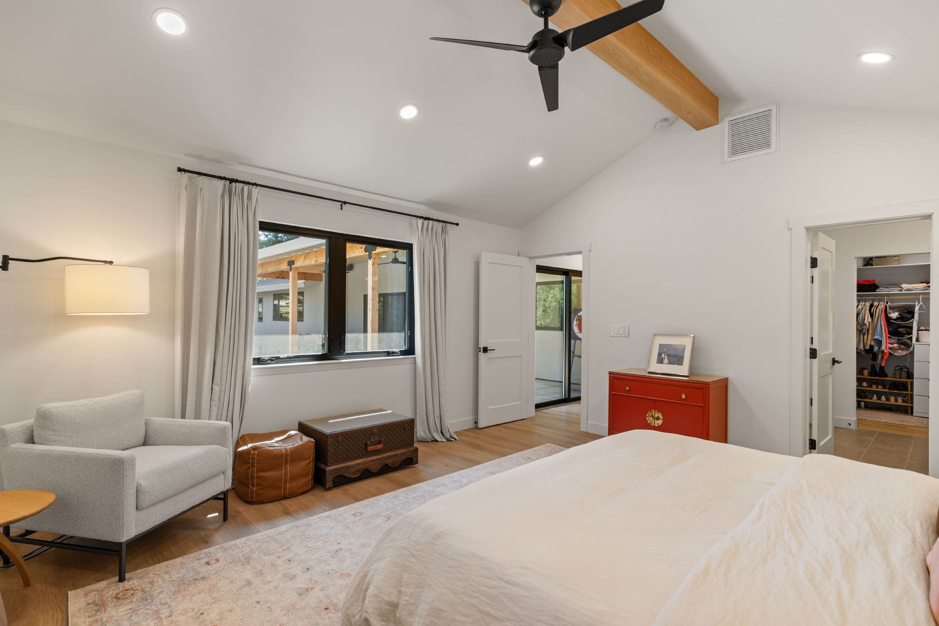 Bright bedroom in Sacramento with red dresser, closet, and neutral palette by H&H Builds