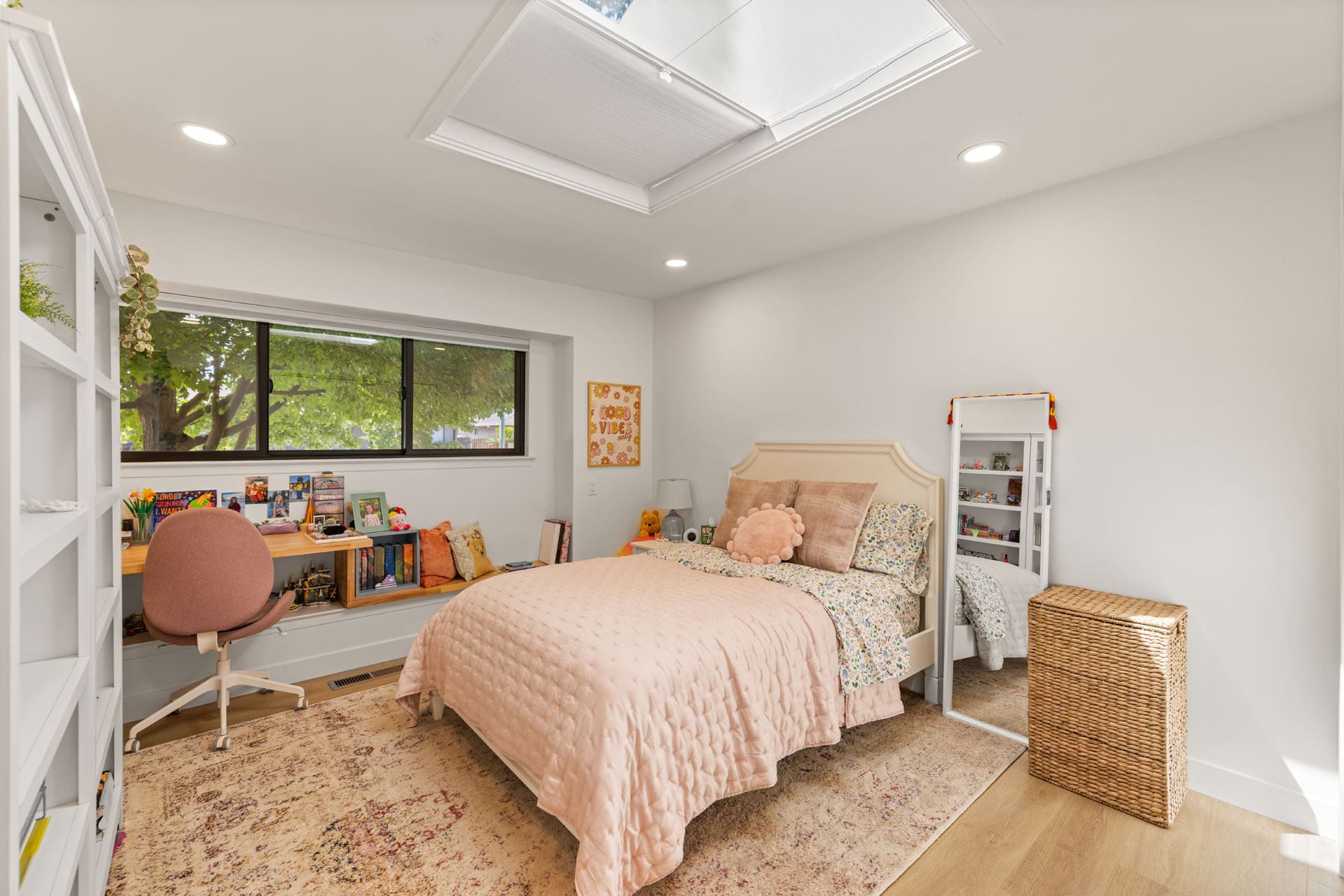 Remodeled bedroom by H&H Builds in Sacramento with skylight, pink bedding, and long desk with books and art Remodeled bedroom by H&H Builds in Sacramento with skylight, pink bedding, and long desk with books and art