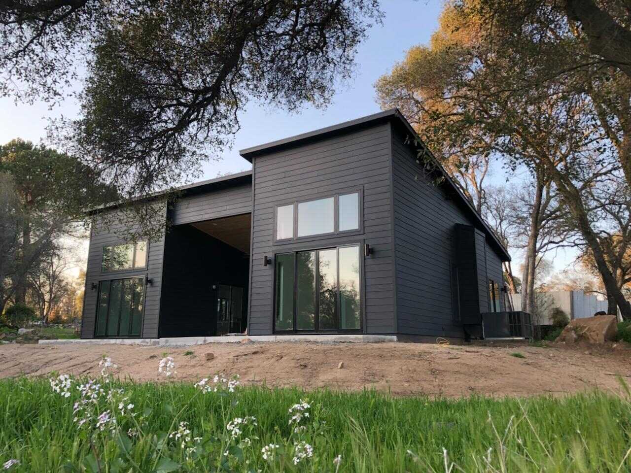 Modern custom-built black exterior home surrounded by trees in Sacramento, CA, by H&H Builds